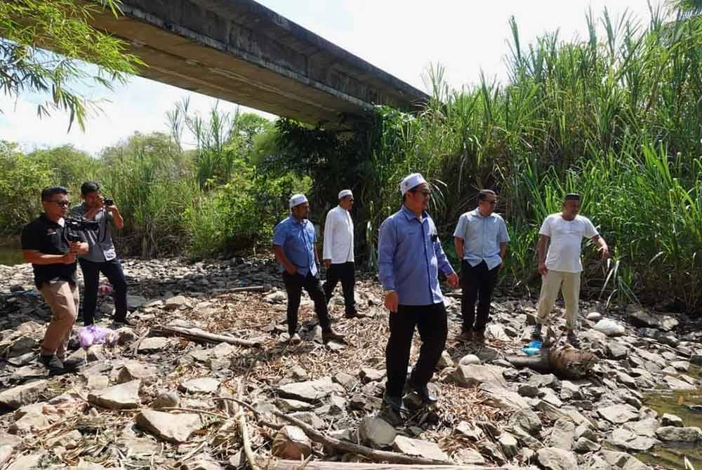 Tuan Mohd Saripudin (depan) meninjau kawasan yang mengalami kemarau di Selising, Pasir Puteh.