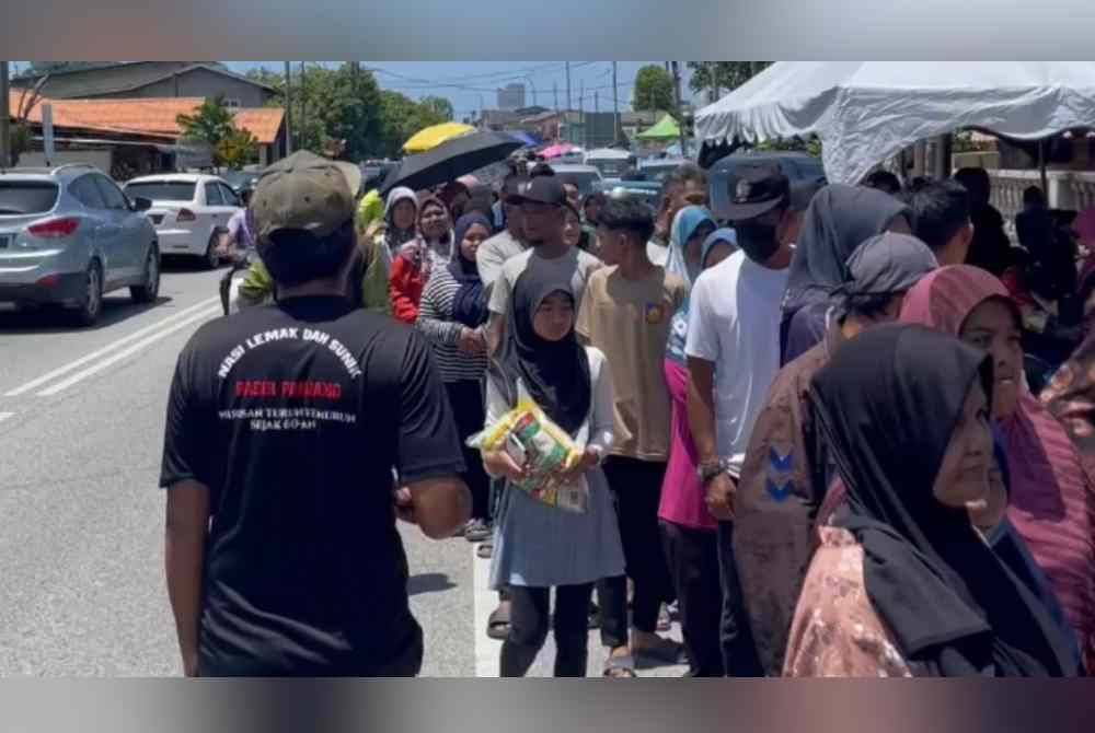 Orang ramai beratur panjang untuk mendapatkan beras percuma yang diagihkan di sebuah kedai runcit di Kuala Terengganu.
