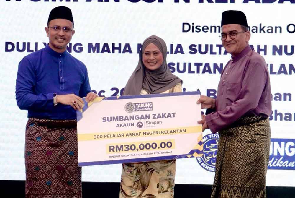 Ahmad Dasuki (kiri) menyerahkan replika cek berjumlah RM30,000 kepada Mohd Zamri (kanan) sambil disaksikan Norasni.