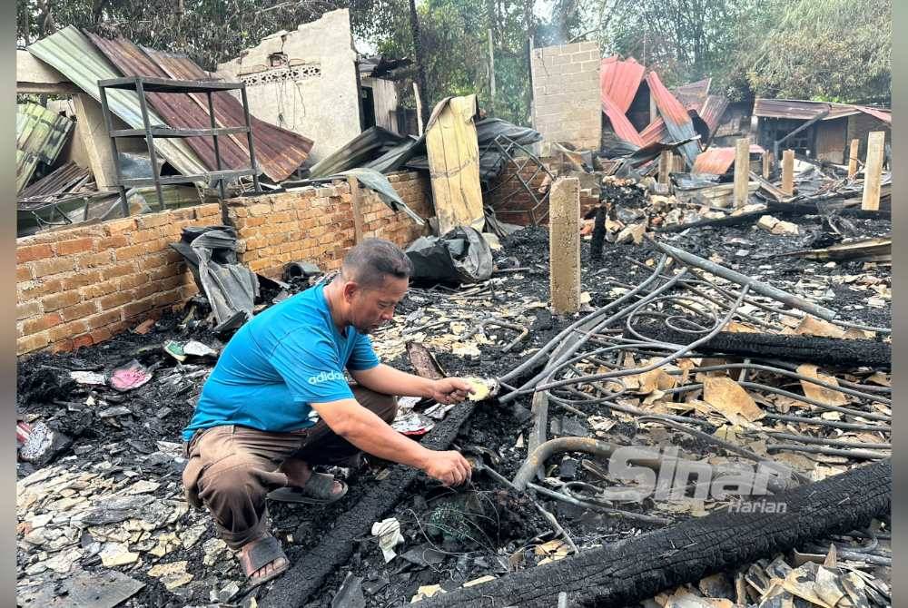 Mat Azhar melihat sisa pakaian yang hangus dalam kebakaran rumahnya.