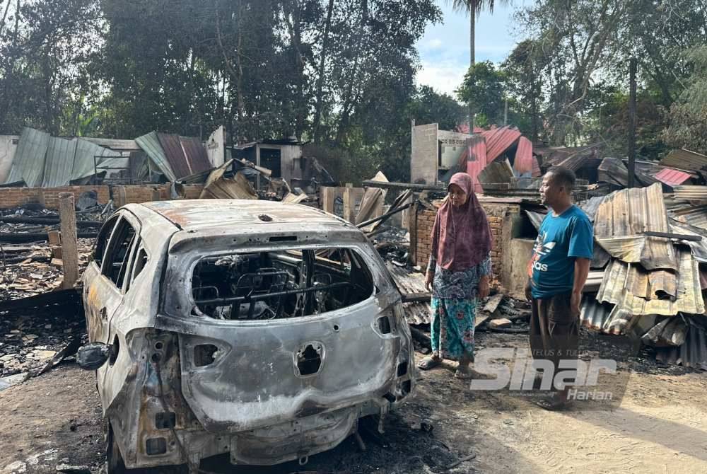 Asiah (kiri) dan Mat Azhar (kanan) melihat kesan rumah mereka yang terbakar.
