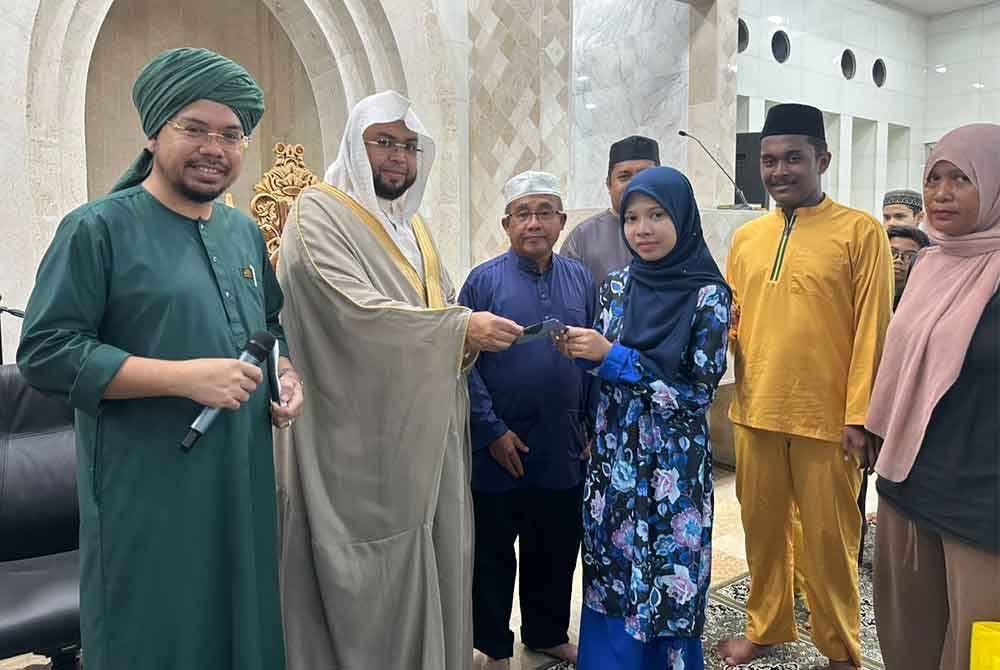 Ibrahim (tiga dari kiri) mengiringi Sheikh Abdul Karim (dua dari kiri) menyampaikan sumbangan zakat.