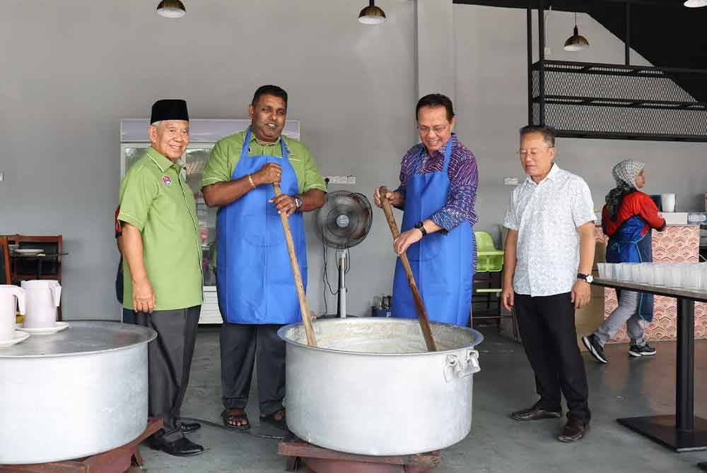 Hasni (dua dari kanan) mengacau bubur lambuk pada program Jelajah Seni Ramadan berbuka puasa di Masjid Pekan Parit Tengah, Benut pada petang Jumaat.