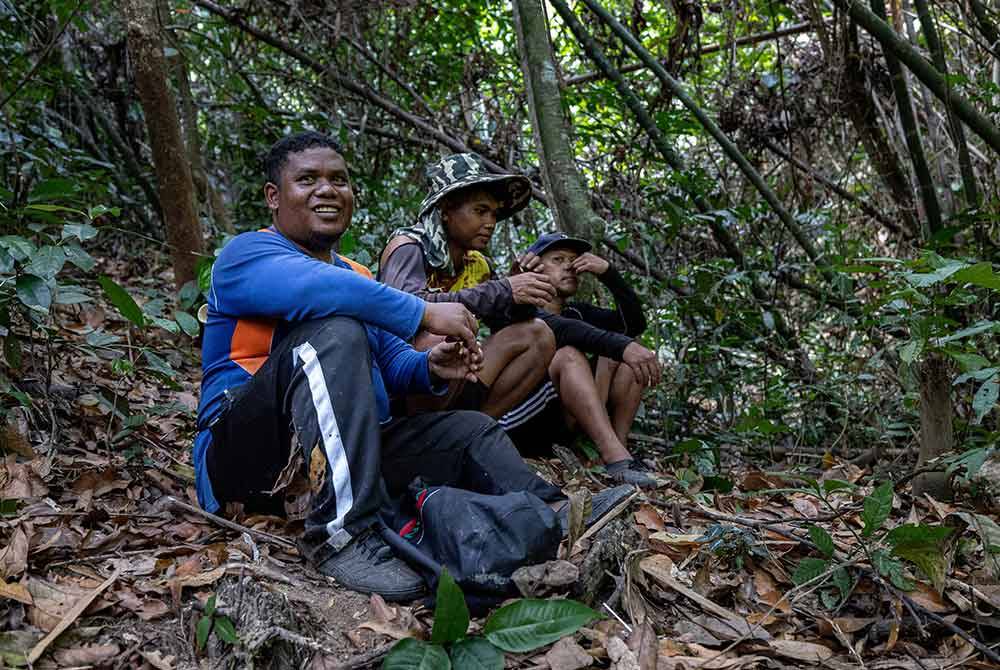 Dari kiri: Jaminan, Baharuddin dan Arman berehat seketika sebelum membawa buluh lemang yang sudah ditebang. Foto Bernama