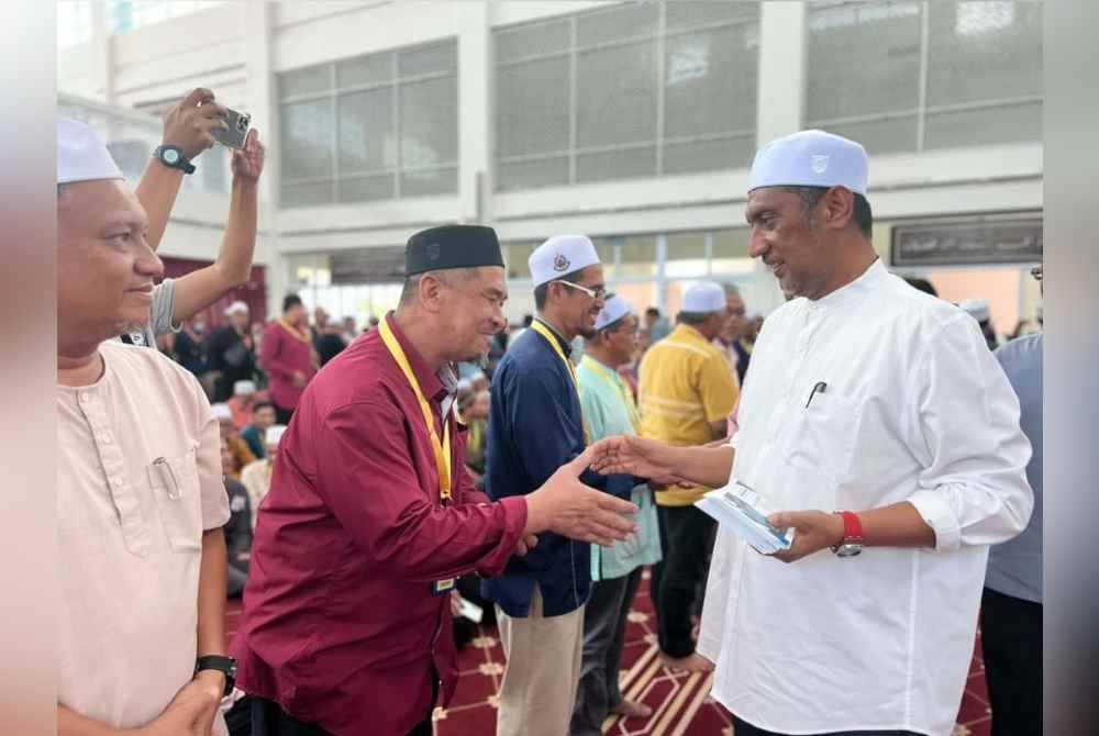 Syed Ibrahim (kanan) menyampaikan bantuan khas Aidilfitri kepada pegawai masjid pada majlis penyampaian di Masjid Sultan Ahmad Shah, Temerloh pada Ahad.