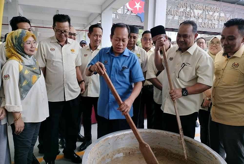 Ahmad ( tengah) bersama warga JKR Johor mengacau bubur lambuk di Cawangan Kejuruteraan Mekanikal, Gelang Patah pada Ahad.