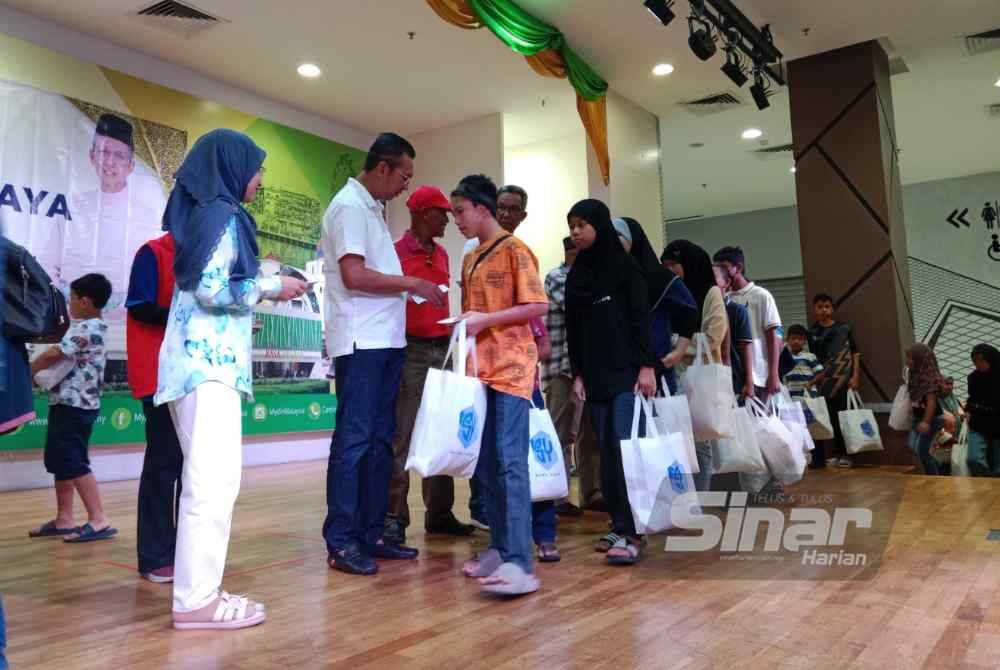 Saiful Yazan (dua dari kiri) menyampaikan duit raya kepada peserta.