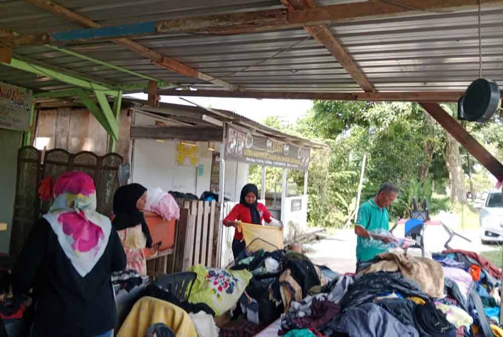 Orang ramai memilih baju raya percuma yang terdapat di Warung Mama Ria, Kampung Sentosa, Pasir Gudang.
