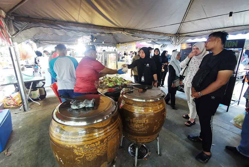 Muhammad Muslim (dua dari kiri) melayan pelanggan yang ingin mendapatkan ayam payang dragon.