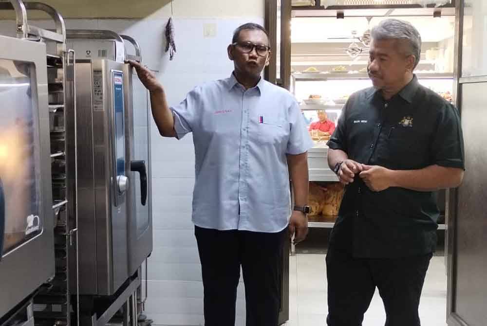 Norshahrizan (kiri) menunjukkan mesin memasak nasi beriani di restorannya.