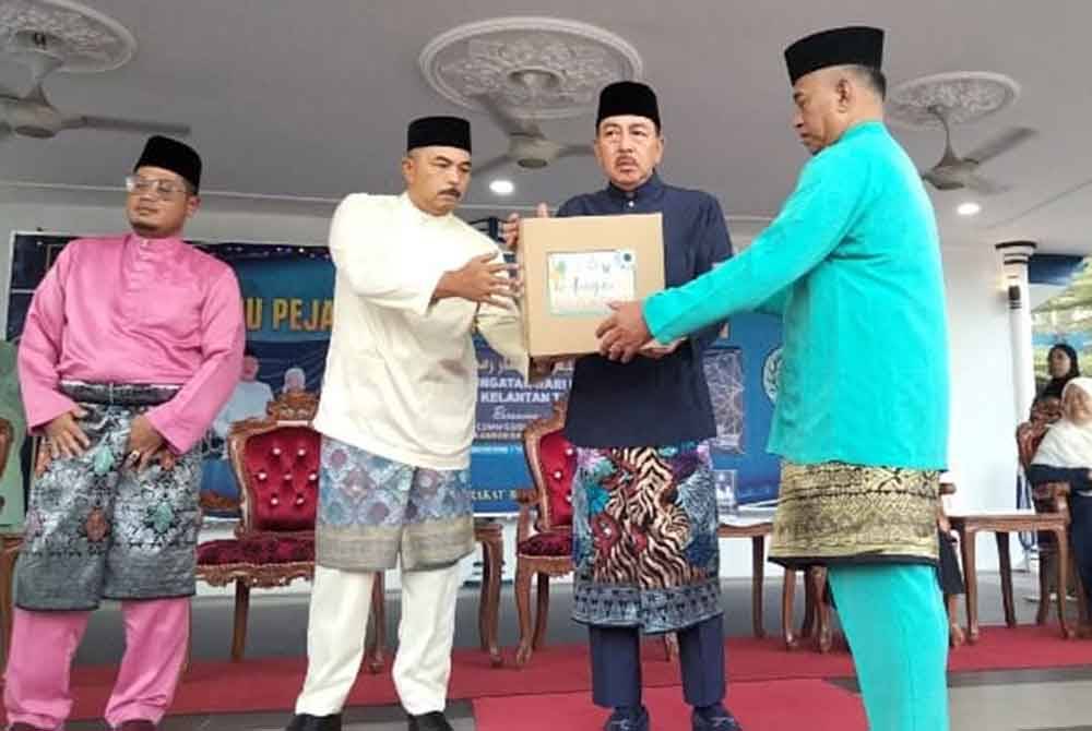 Muhamad Zaki (dua dari kanan) menyampaikan bakul makanan kepada pegawai polis sempena Majlis Iftar Ramadan Perdana Peringkat Kontinjen Kelantan Sempena Peringatan Hari Polis Ke-217 di sini pada Ahad.
