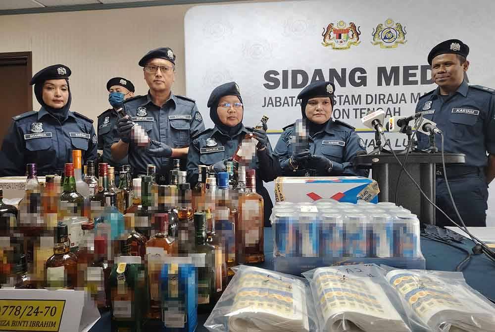 Norlela (tengah) menunjukkan minuman keras yang dirampas dalam serbuan di sebuah premis menjual minuman keras di Bandar Saujana Putra, Kuala Langat, 14 Mac lalu.