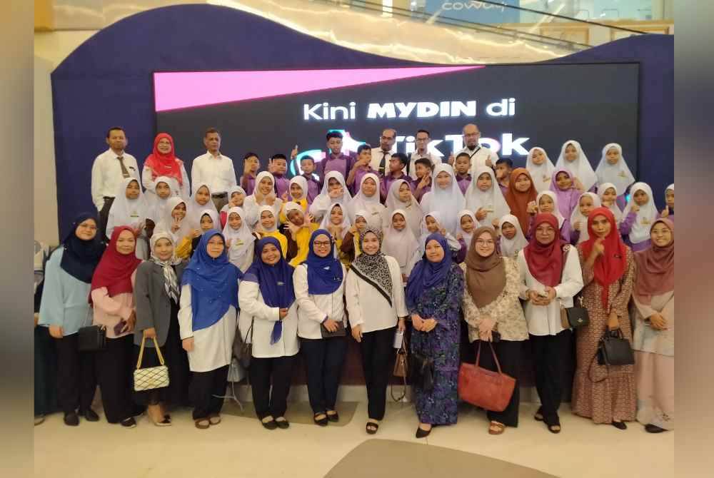 Zahar (belakang, tiga dari kiri) bersama penerima sumbangan dan guru-guru bergambar sebelum membeli pakaian hari hari raya di Pasar raya Besar Mydin Meru di sini pada Isnin.