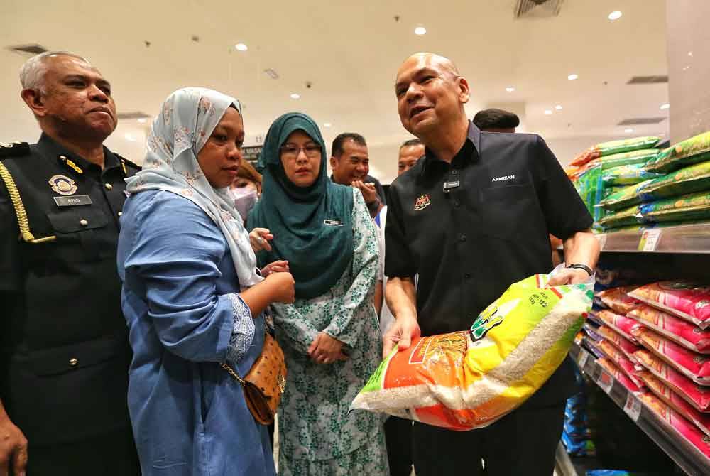 Armizan (kanan) mengangkat beras putih tempatan di sebuah pasar raya di Nilai.