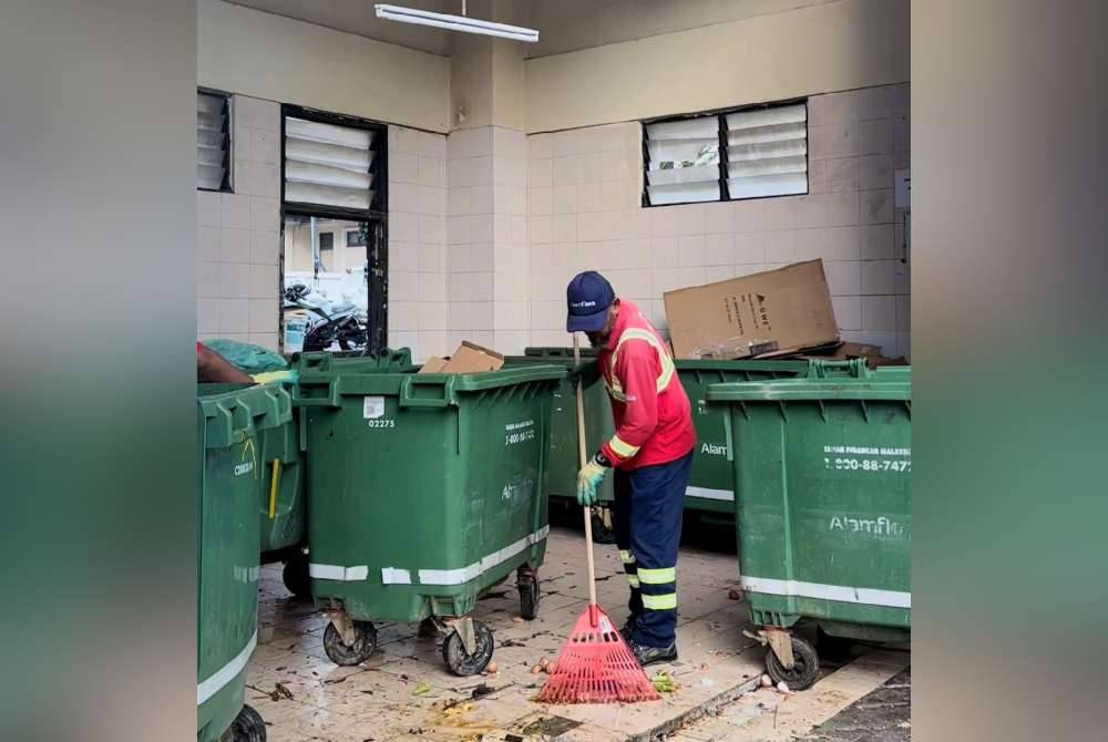 Pekerja Alam Flora membersihkan bahagian rumah sampah selepas mengutip sisa pepejal yang dibuang oleh orang ramai.