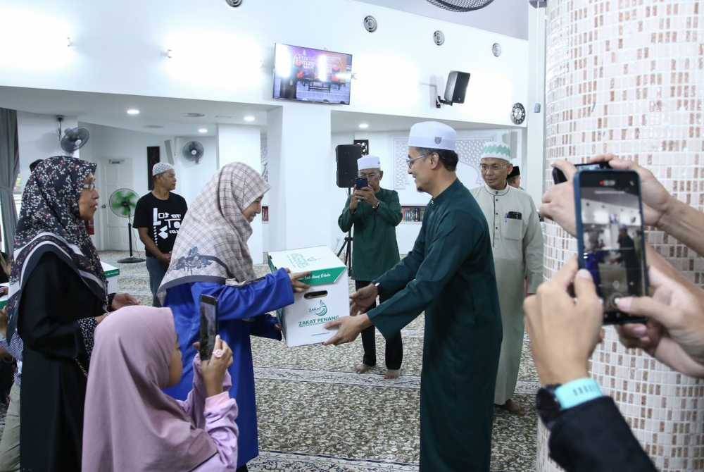 Mohamad menyerahkan bantuan dan saguhati kepada salah seorang asnaf yang hadir di Majlis Penyerahan Saguhati Hari Raya Fakir Miskin ZPP di Masjid Al-Huda Sungai Ara.