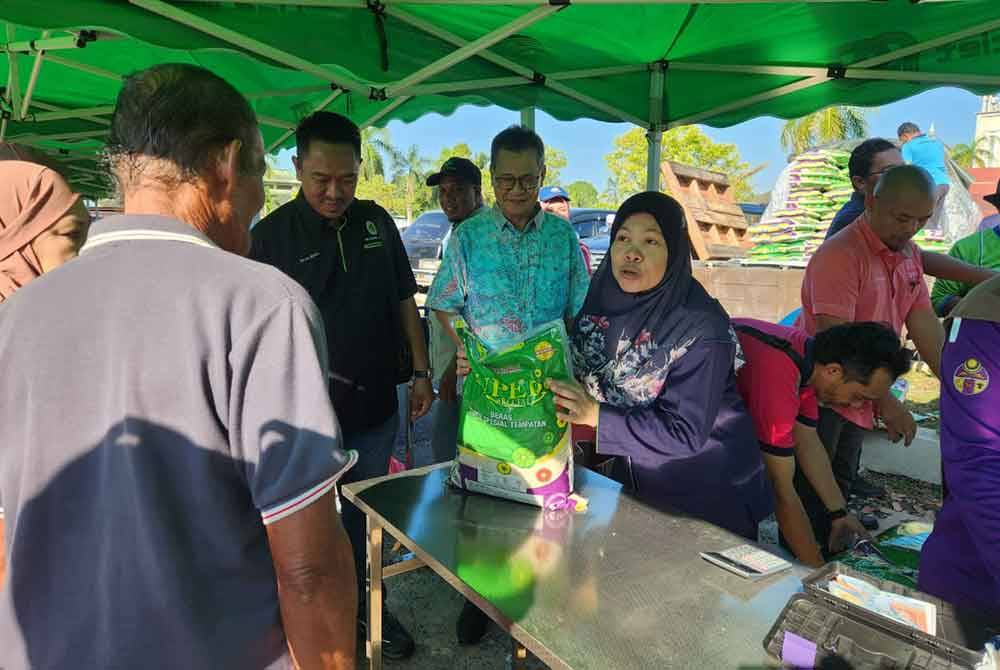 Hasmila (tengah) mengagihkan beras yang dijual pada program Jualan Agro Madani LPP Terengganu pada Rabu.