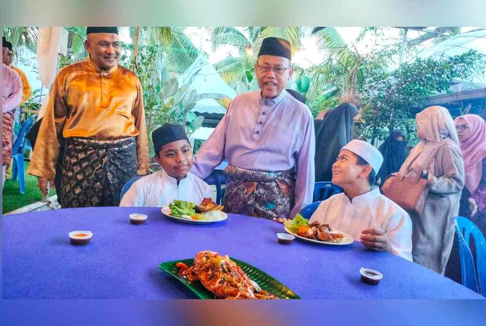 Abdul Fattah (tengah) bersama Mohamad Hanifah (kiri) menyantuni kanak-kanak pada majlis berbuka puasa dan penyerahan sumbangan untuk asnaf oleh Angkasa Zon II Pahang Tengah di Amani Vanila Temerloh di Temerloh pada Selasa.
