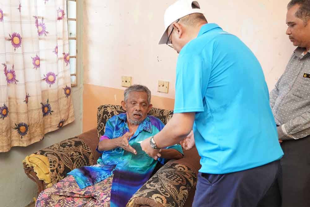 Burhanuddin Hilmi (tengah) memberi sumbangan pada Rosli.