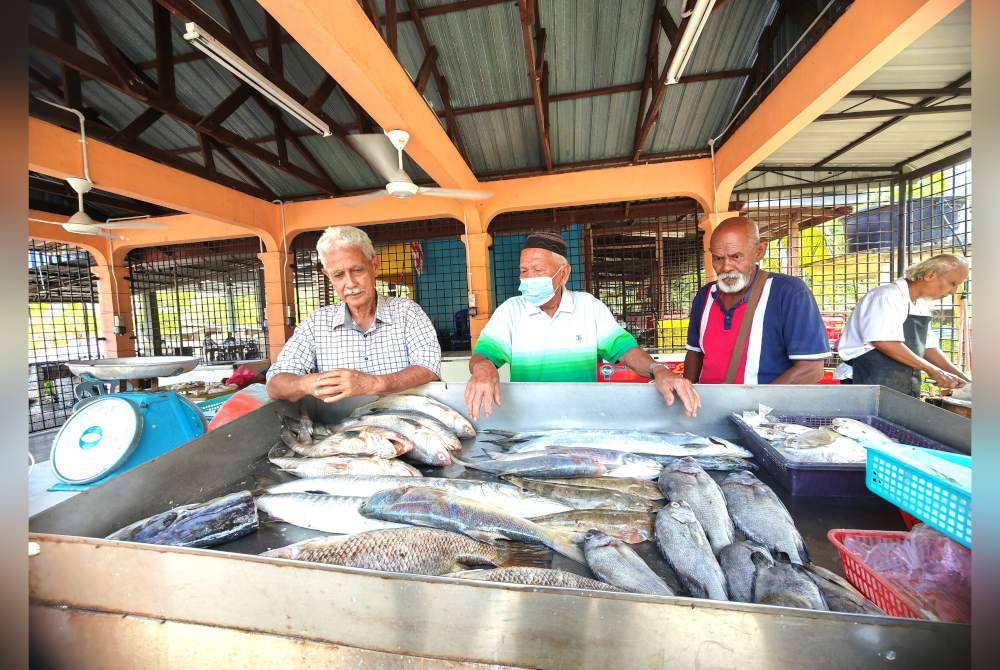 Ayup (kanan) melihat ikan yang dijual di pasar ikan di pasar di Persatuan Nelayan Teluk Kemang.