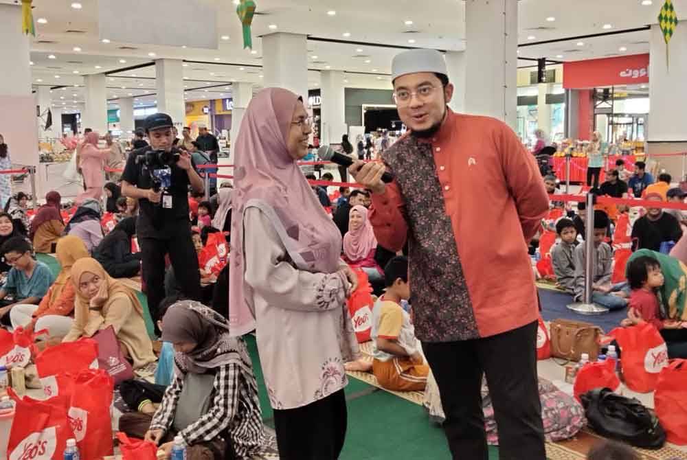 PU Rahmat (kanan) bertanyakan soalan kuiz kepada pengunjung Mydin yang menyertai Iftar Ala Madinah di Mydin Tunjong pada Rabu.