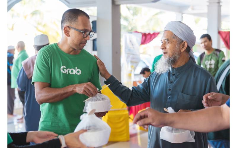 Rashid (kiri) menyampaikan sumbangan bubur lambuk kepada salah seorang penduduk setempat.