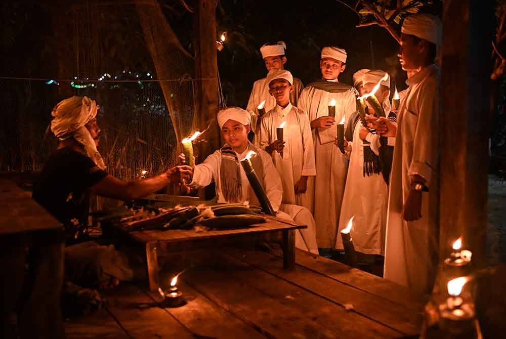 Mohd Zailani Mohd Nor, 49, (kiri) mengagihkan pelita kekabu kepada pelajar Kompleks Pendidikan Tahfiz An Nur Besut yang ingin merasai pengalaman memegang pelita itu sempena malam tujuh likur semasa ditemui di rumahnya di Kampung Alor Belanga, semalam.