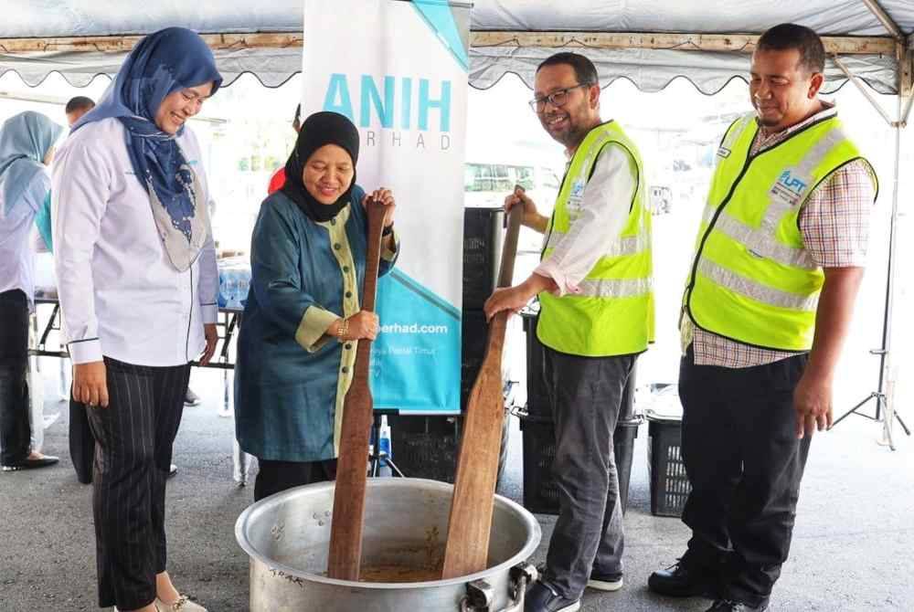 Radzimah (dua dari kiri) turun padang mengacau bubur lambuk. Foto Anih Berhad