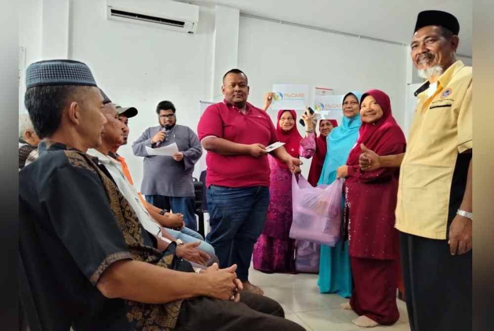 Azmi (kanan) mengiringi Dr Hafidzah menyampaikan sumbangan daripada MyCare dan DUN Kota Lama