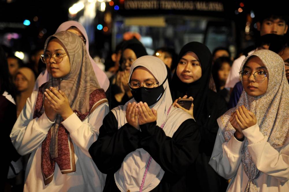 Sebahagian penuntut UTM mengaminkan doa sebelum menaiki bas untuk pulang berhari raya dalam Program Jom Balik Raya di Dataran UTM Skudai, Johor Bahru.