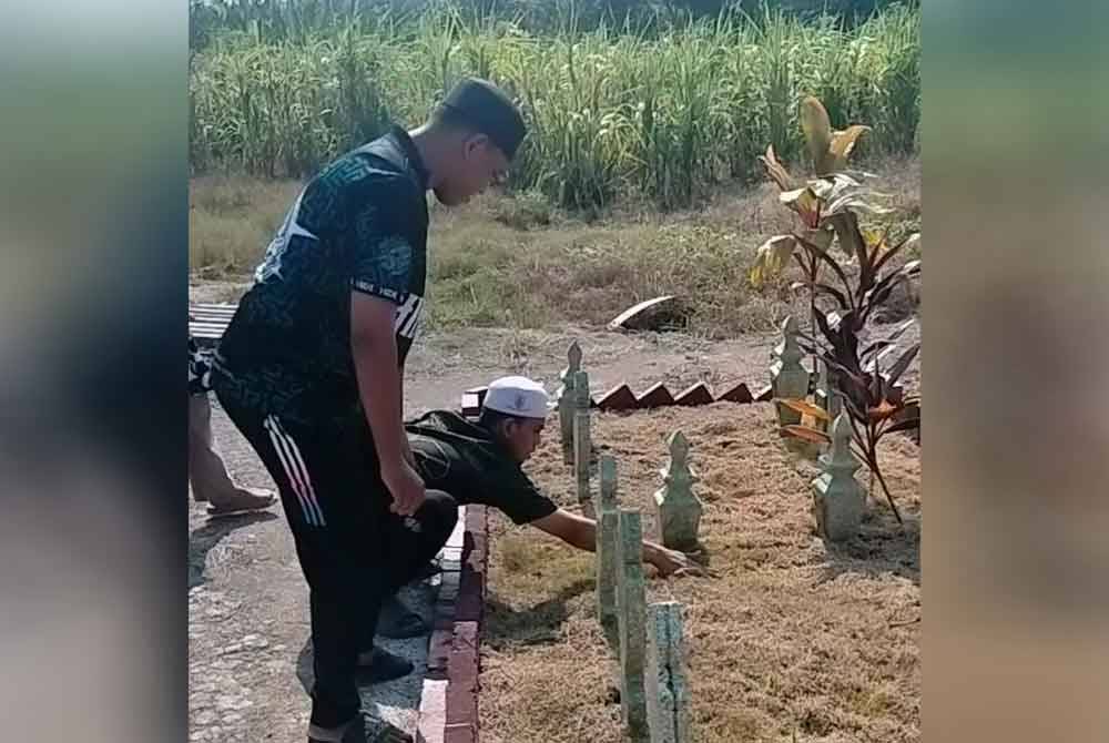 Abdullah (kiri) dan Abdur Rahman membersihkan pusara ayah, ibu dan adik beradik di tanah perkuburan Islam Masjid Jamek Ubuddiah Parit Limbong Muar.