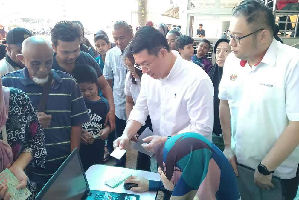 Kor Ming (dua dari kanan) bersama penerima sumbangan ketika Program Meriah Beraya Sejahtera Bersama Dewan Undangan Negeri (DUN) Kepayang di sebuah pusat beli-belah di sini pada Sabtu.