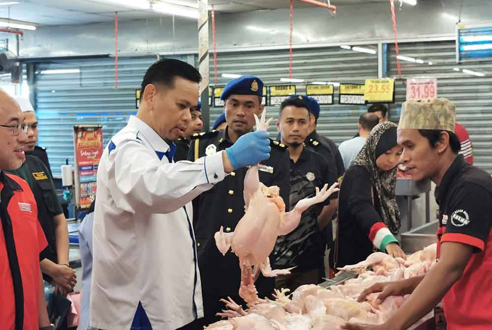 Saharuddin memegang seekor ayam ketika tinjauan dbahagian bahan mentah di pasar raya tuncit itu.