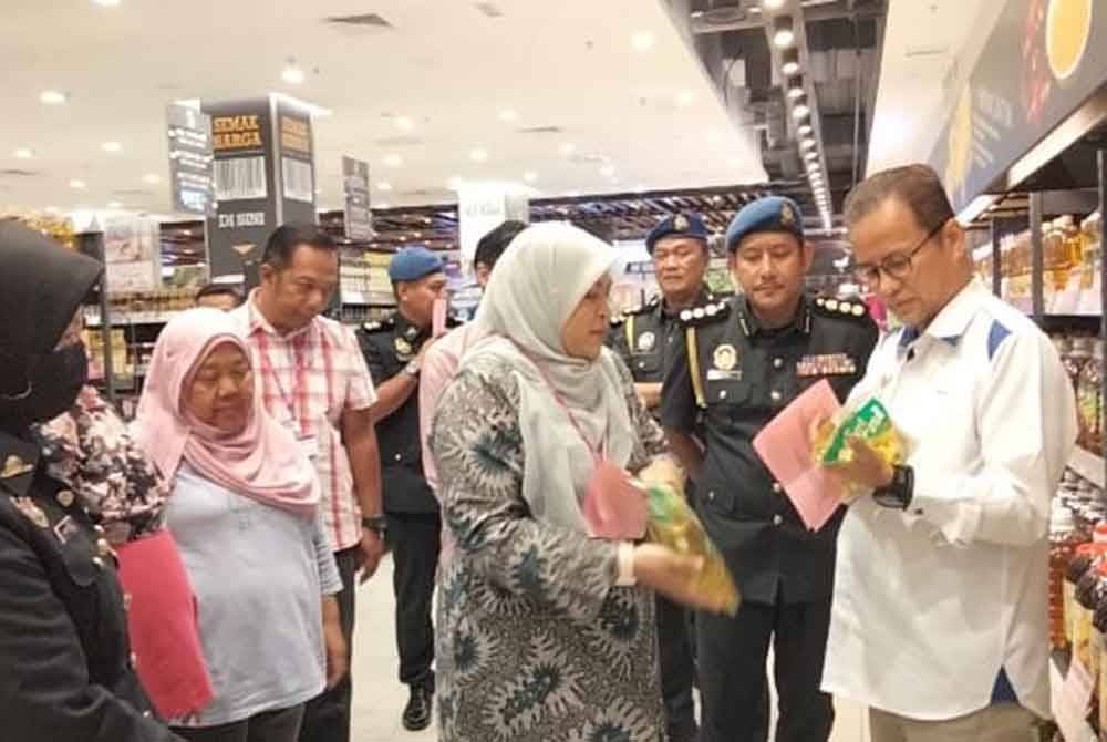 Azman (kanan) melihat minyak masak di sebuah pasar raya Program Walkabout Skim Harga Maksimum Musim Perayaan (SHMMP) Hari Raya Aidilfitri 2024 di sini.