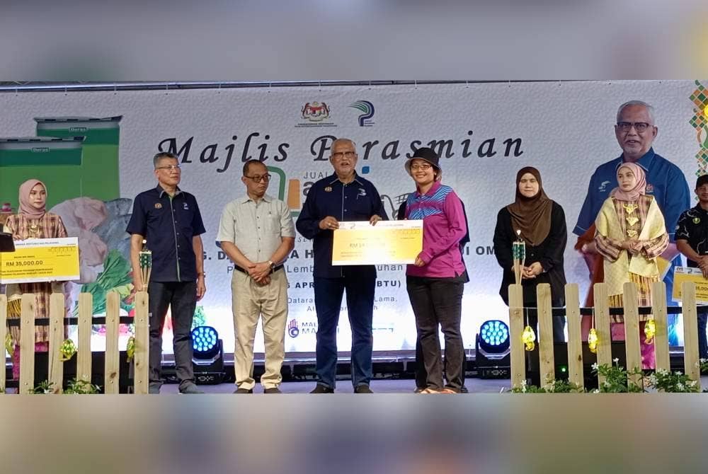Mahfuz (tiga,kiri) menyerahkan geran kepada penerima pada program Jualan Agro Madani Mega Raya di Dataran Jalan Istana Lama pada Sabtu.