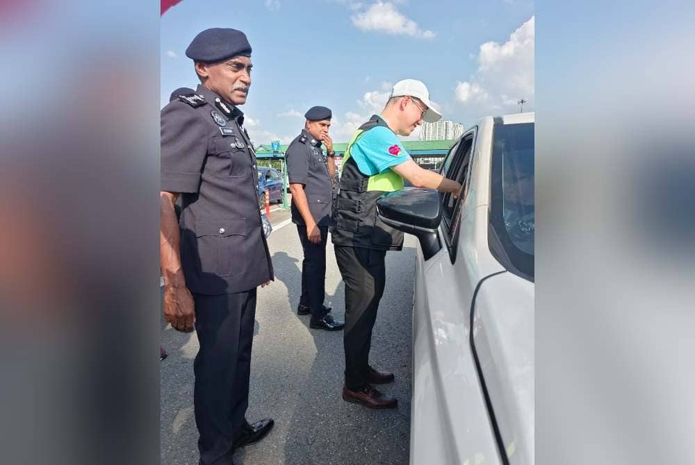 Kumar (kanan) dan Sing Chuan (kiri) pada Program Advokasi Keselamatan Jalan Raya PDRM dan Perkeso sempena Op Selamat Hari Raya Aidilfitri, di Plaza Tol Kempas pada Sabtu.