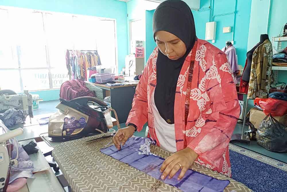 Nor Rashidah memastikan ketelitian dalam memotong kain untuk dijadikan baju kurung sebagaimana ditempah pelanggan.
