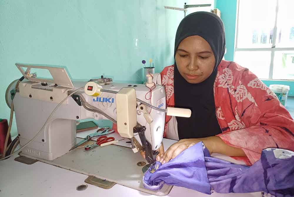 Nor Rashidah menyiapkan tempahan pelanggan di kedai jahitnya di Putra Square pada Ahad.