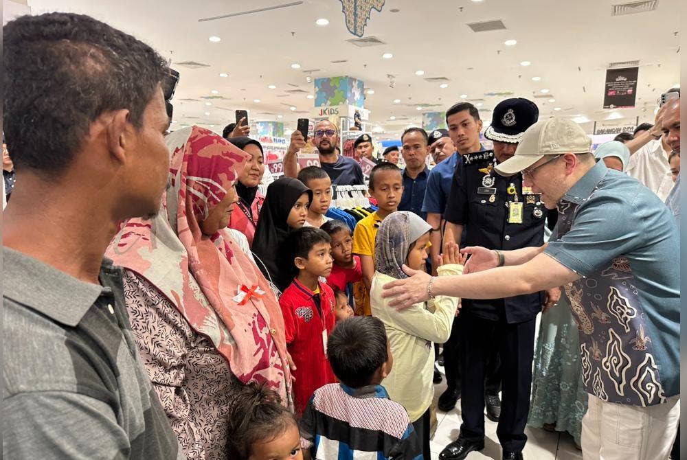 Tengku Muhammad Fakhry (kanan) memakaikan baju raya kepada anak sulung Zilawati.