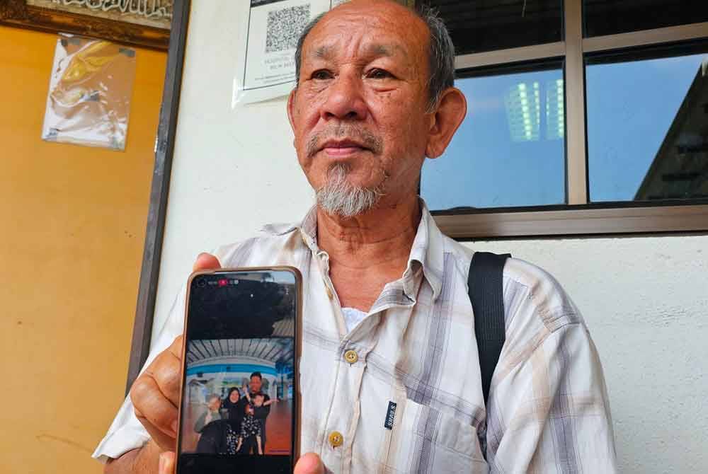 Mat Zainal menunjukkan gambar keluarga anaknya itu yang terlibat dalam nahas di JRTB Gerik -Jeli pada Ahad.