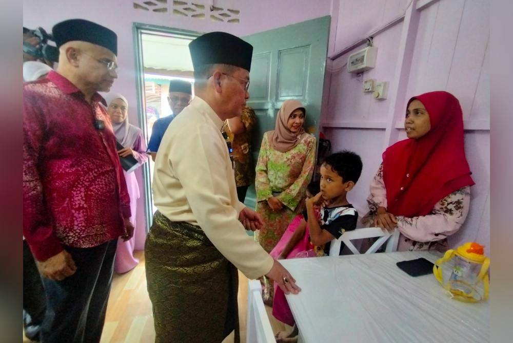 Mohd Na'im meluangkan masa berbual dengan keluarga penerima di Padang Balang.