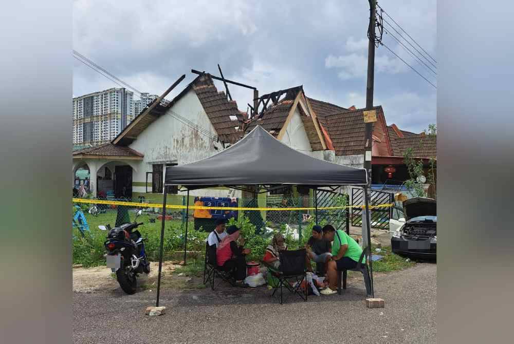 Saipul bersama isteri serta adik dan adik iparnya di bawah khemah di hadapan rumah yang terbakar.