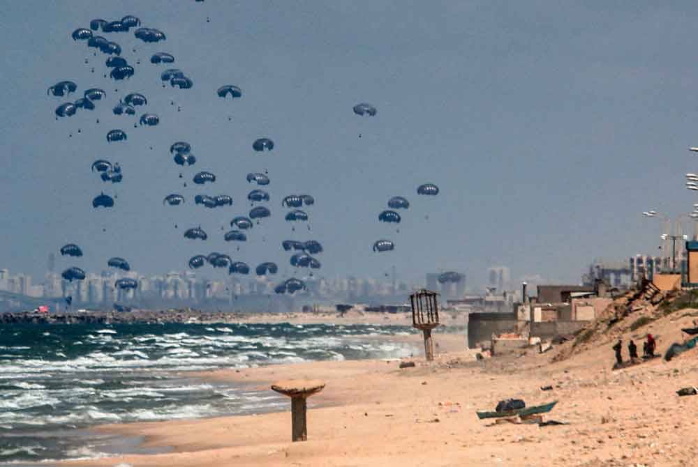 Bantuan kemanusiaan yang digugurkan menggunakan payung terjun di Gaza City hasil kerjasama negara Perancis, Britain dan Jordan. - AFP