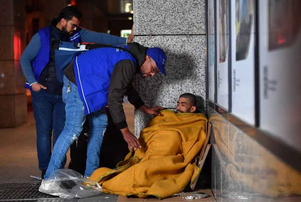 Sukarelawan memeriksa gelandangan yang tidur di stesen pengangkutan awam akibat tidak mampu bayar sewa rumah. Foto AFP