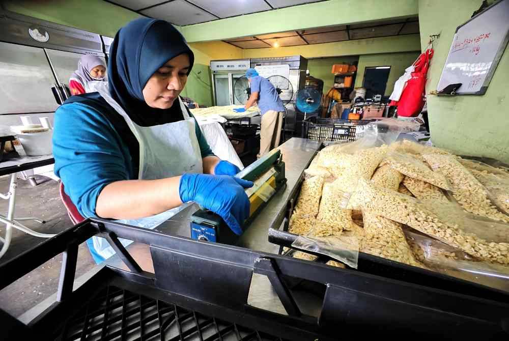 Pekerja Zuhaymee sedang membungkus tempe yang akan dijual kepada pelanggan.