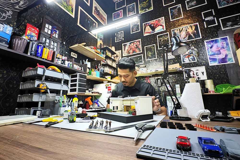 Muhammad Sharil menyiapkan miniatur diorama tempahan pelanggan di pejabatnya