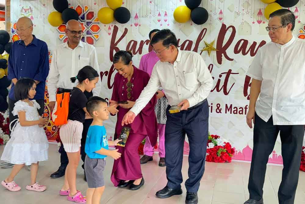 Kon Yeow (dua dari kanan) memberi duit raya kepada kanak-kanak yang hadir ke Karnival Raya Parlimen Bukit Bendera pada Ahad.