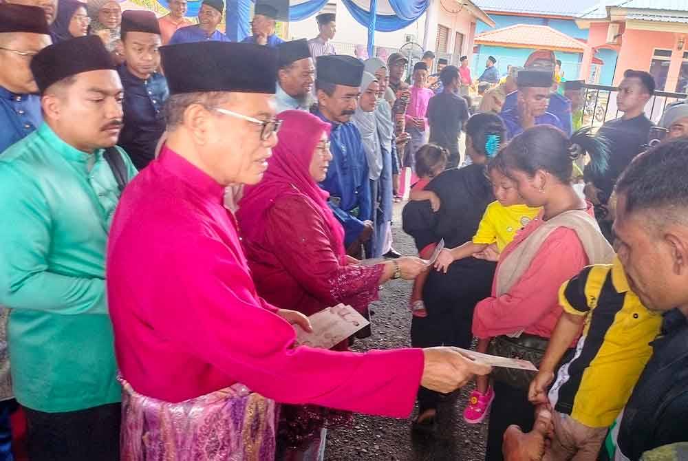 Wan Rosdy mengagihkan duit raya kepada kanak-kanak yang hadir pada Majlis Rumah Terbuka Aidilfitri di Laman Sejahtera Jelai, Felda Sungai Koyan pada Ahad