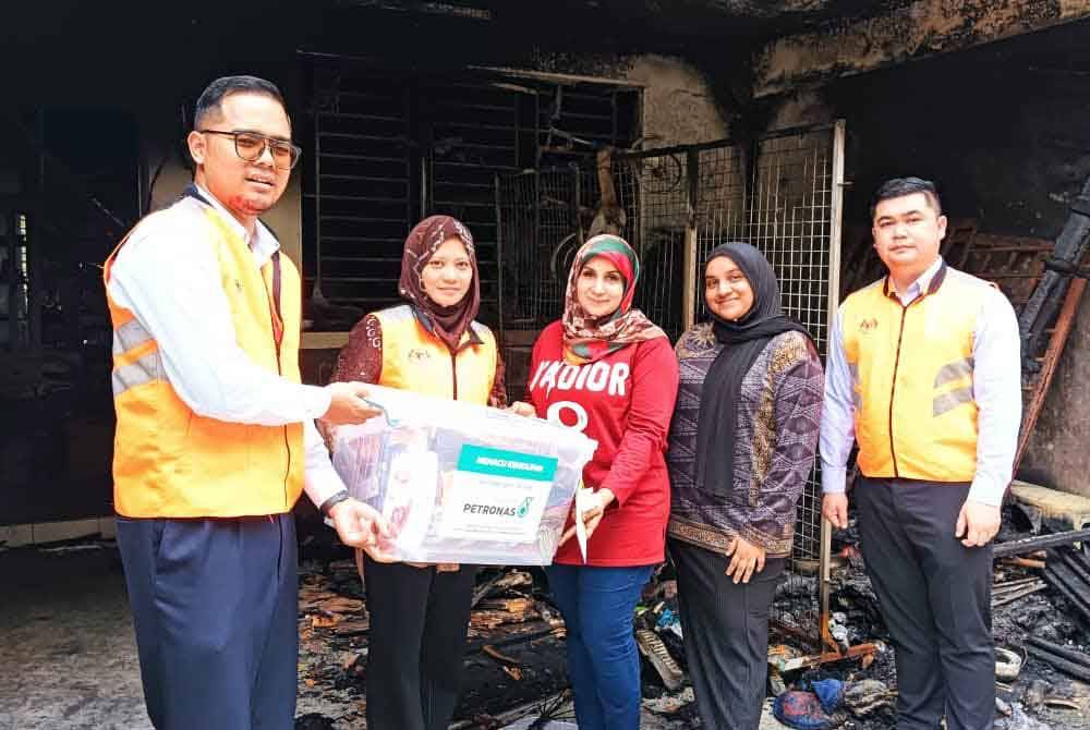 Nor Hafizah (dua kiri) menyampaikan bantuan wang tunai, makanan kering dan barang keperluan kepada Faridah (tengah) dan Nur Farah Syazatul (dua kanan) di rumhanya di Taman Scientex, Pasir Gudang pada Ahad