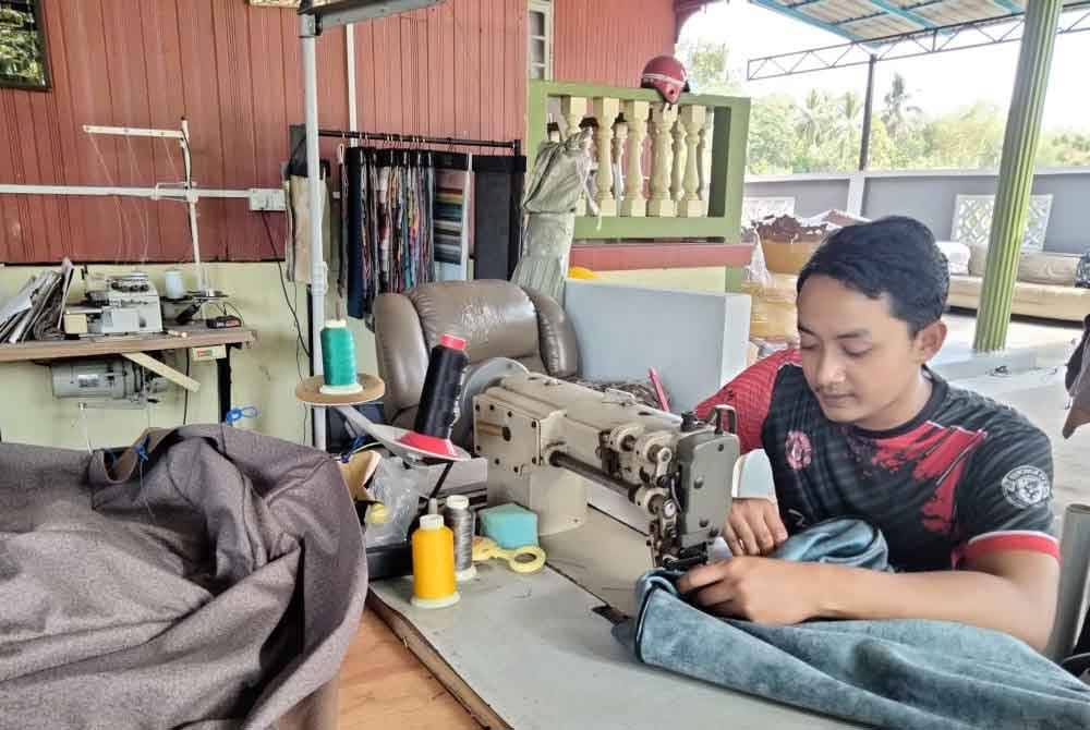 Wan Mohd Zahiruddin menjahit sarung sofa yang akan dibaiki.